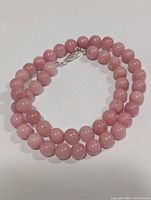 Full view of pink rhodochrosite bead necklace coiled to show length and clasp