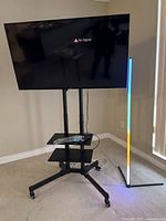 JVC TV mounted on wheeled stand with shelves visible