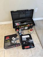 Open Rubbermaid toolbox, Dremel case, inverter box, aerosol cans, tape