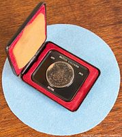 Coin in open red display case showing heavy tarnish