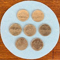 Seven Canadian dollar coins arranged on blue felt shown front side