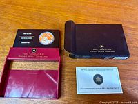 Coin in maroon display holder alongside outer sleeve