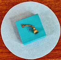 Watch fob on blue box showing overall size and shape