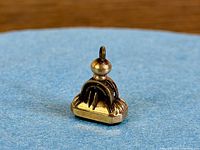 Side view of gold-filled watch fob showing arched openwork frame and suspension loop