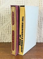 Both books standing in slipcases showing spines