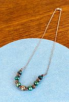 Full view of sterling silver necklace with multicolor Tahitian pearls on blue background