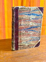 Front and spine view of antique half-leather book showing marbled boards and wear