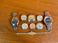 Group shot of ten wristwatches on wooden surface