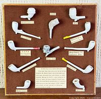 Full view of board with eleven clay pipes and labels
