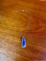 Full view of sterling necklace and turquoise pendant on wooden surface