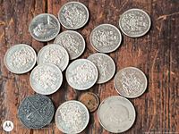 Group of Canadian 50-cent coins, cob commemorative and small bronze coin displayed on wood surface