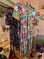Two dresses hanging: multicolor floral short-sleeve and black floral long-sleeve