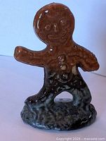 Front view of brown glazed gingerbread man figurine on base
