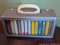 Front view of grey plastic carry case with handle and cassette tapes visible