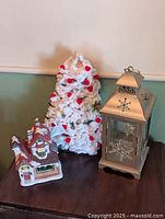 Group shot of all three festive decor items: yarn tree, lantern, ceramic building