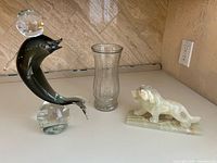 Overall view showing glass dolphin figurine, clear vase, onyx lion statue