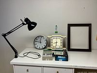 All items grouped on surface: lamp, two clocks, frame, boxed key cabinet, calculator
