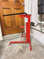 Front view of red floor corking machine showing lever and bottle platform