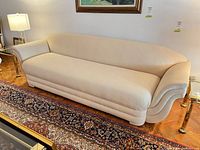 Full view of cream upholstered sofa on hardwood floor with side tables