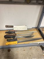 Six implements laid out on shelf: cleaver, steel, four knives