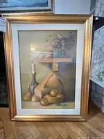 Full view of framed still life oil painting leaning against wall