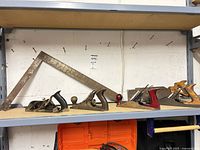 Shelf view showing all four planes, hand saw partially, and framing square