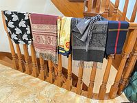 All five scarves draped over railing, showing patterns and colors