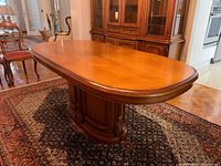 Full view of oval wood dining table showing top and pedestal base