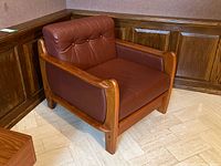Front angle view of teak armchair showing frame and leather upholstery