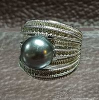 Front view showing textured multi-row band and central grey pearl