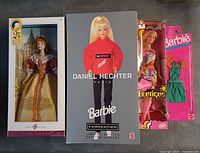 Front view of four packaged Barbie items: two dolls and two outfits