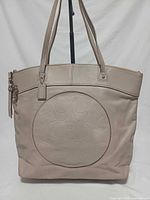 Front view showing entire tote, embossed circle logo, handles, hardware