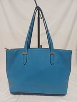 Front view of blue leather Coccinelle tote showing overall shape and handles
