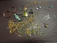 Overview of assorted necklaces, bangles, cuffs, pendants on brown surface