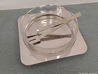 glass bowl atop stainless platter with utensils