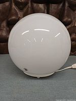 Front view of white glass globe lamp, cord visible