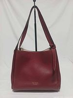 Front view of red pebbled leather Kate Spade Knott handbag showing straps and knot detail