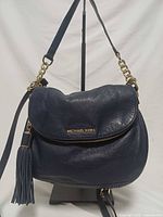 Front view showing navy pebbled leather, tassel, gold hardware and Michael Kors logo