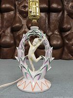 Front view of porcelain Art Deco figurine lamp without bulb, showing painted details and socket