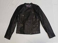 Full front view of black leather Danier biker jacket laid flat