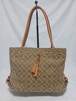 Front view of monogram canvas tote with leather straps and tassel