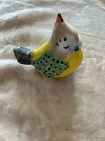 front angled view of yellow and green dotted porcelain bird