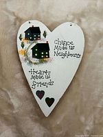 Front view of heart-shaped plaque with painted houses, quote, decorative hearts