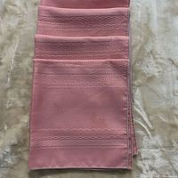 Stack of folded pink napkins showing color, fabric texture and hem