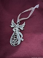 Front view of pewter angel ornament with ribbon