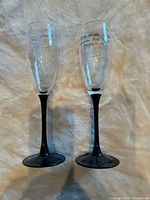 Front view of both clear etched champagne flutes with black stems