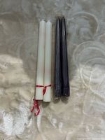 two white candles tied with ribbon beside two plastic-wrapped purple candles