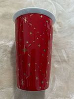 Side view of red porcelain mug showing gold star pattern