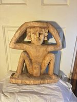 Front view of entire wooden figure showing seated pose and overall condition