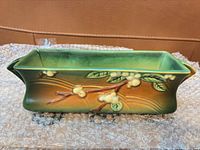 Front view of rectangular Roseville planter showing green and brown glaze with raised white berry branch design